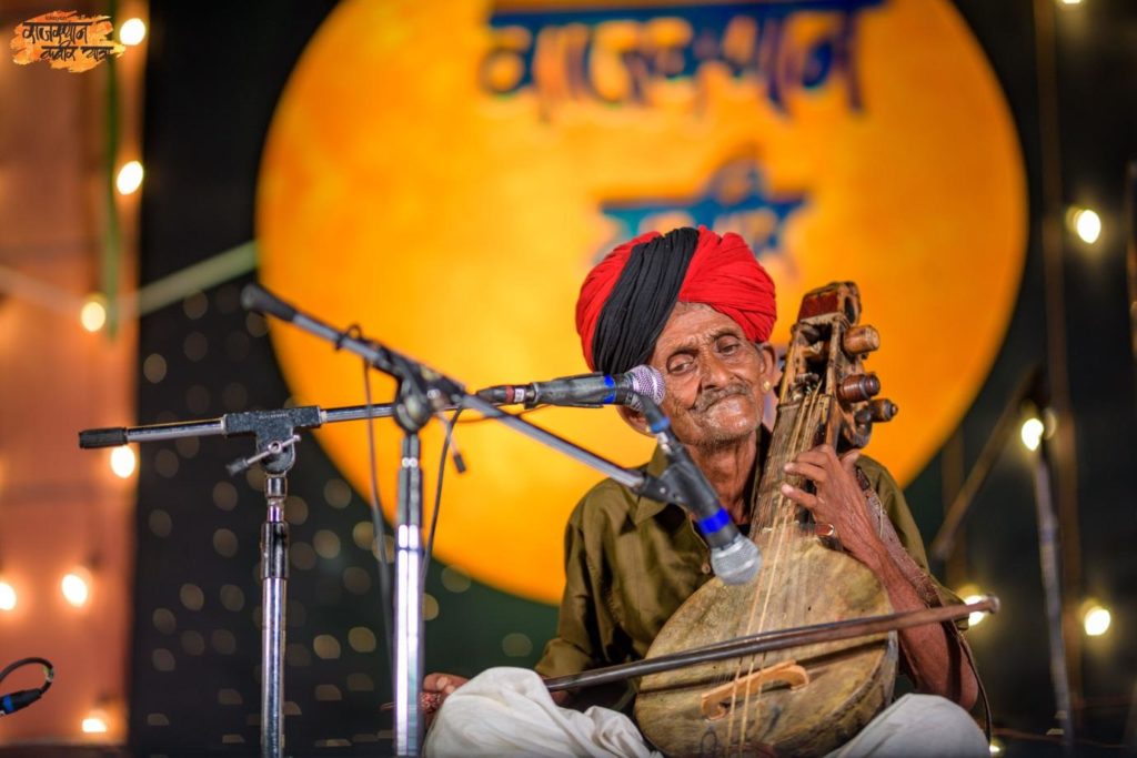 The photograph exhibits Late Dapu Khan Mirasi, performing at the Jawahar Kala Kendra, Jaipur at the 2019 Rajasthan Kabir Yatra. Photo: Jawahar Kala Kendra, Jaipur